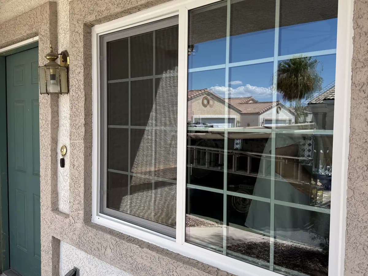 Large window with white grilles beside a covered entry door.