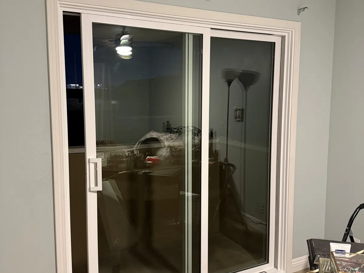 Wide sliding patio door in a living room, white frame, wood floor.