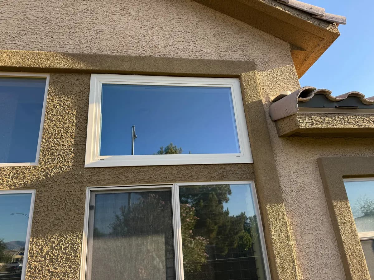 Picture window and lower windows on a tan stucco corner under a tile roof.