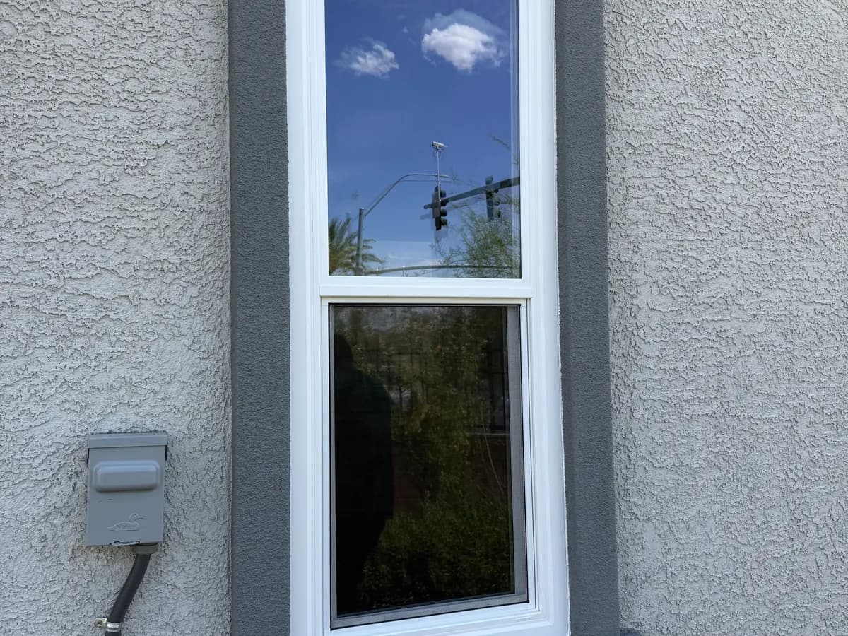 Single-hung window with grey surround in a stucco wall.