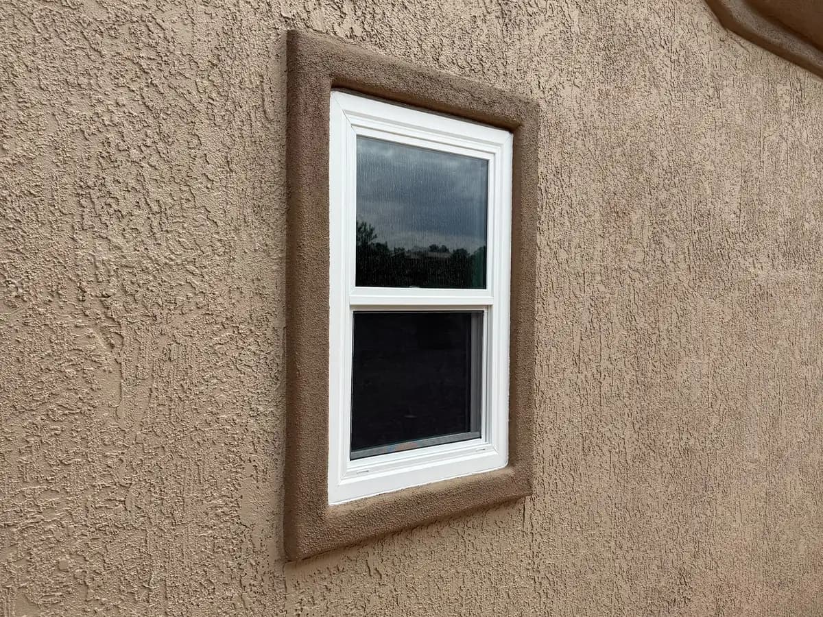 Small Single-Hung window in a recessed tan stucco surround.
