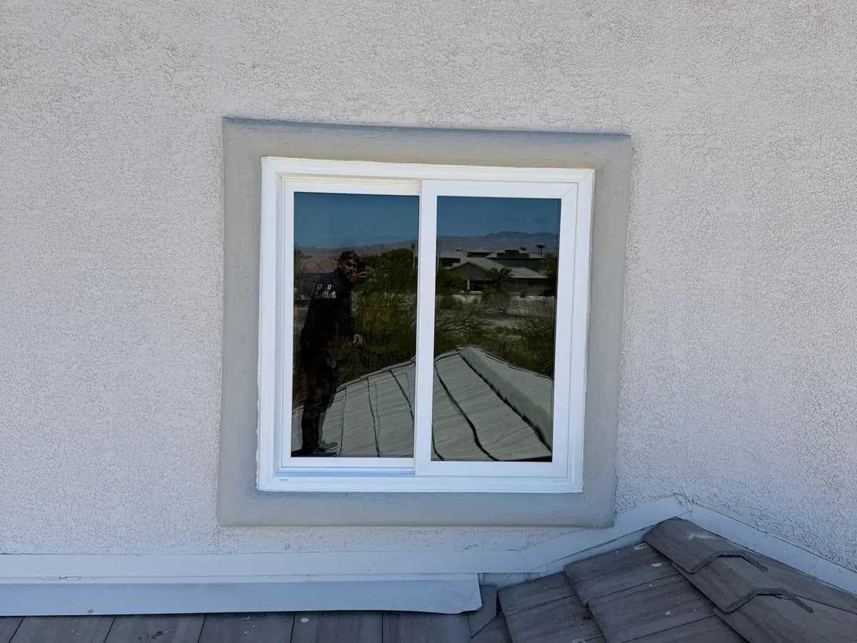 White sliding window above a tile roof.