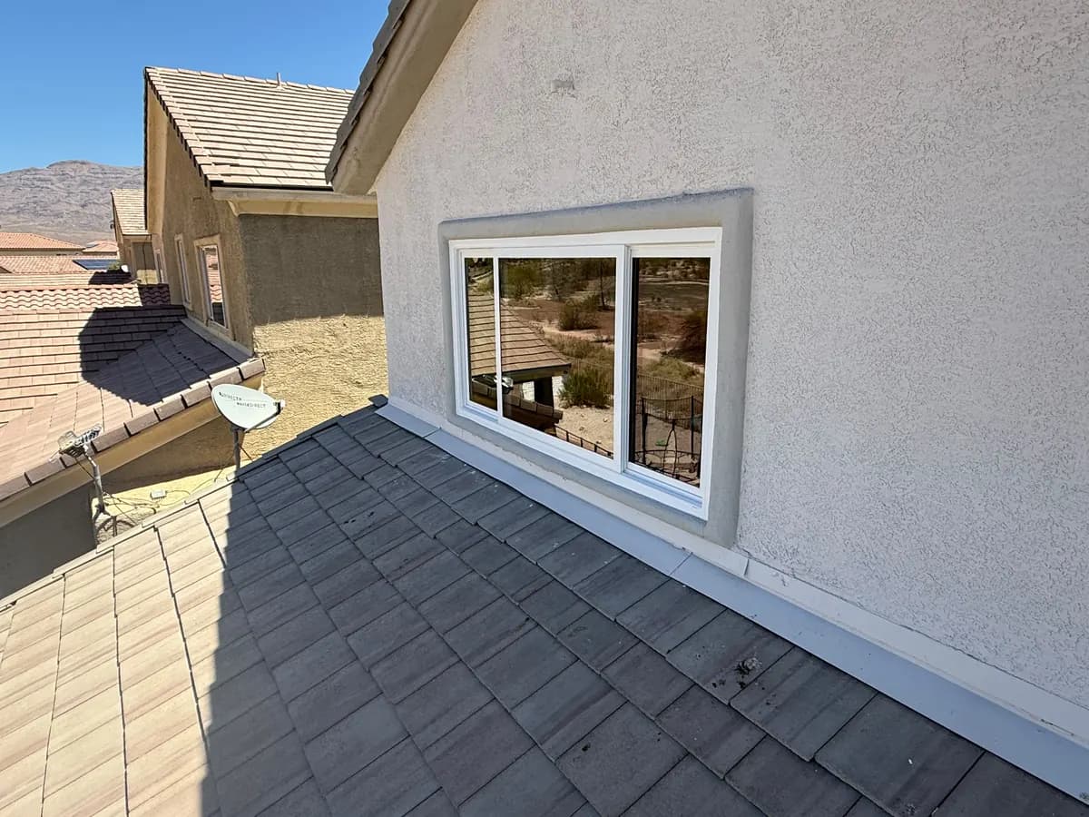 White sliding window in stucco, seen from the roofline.