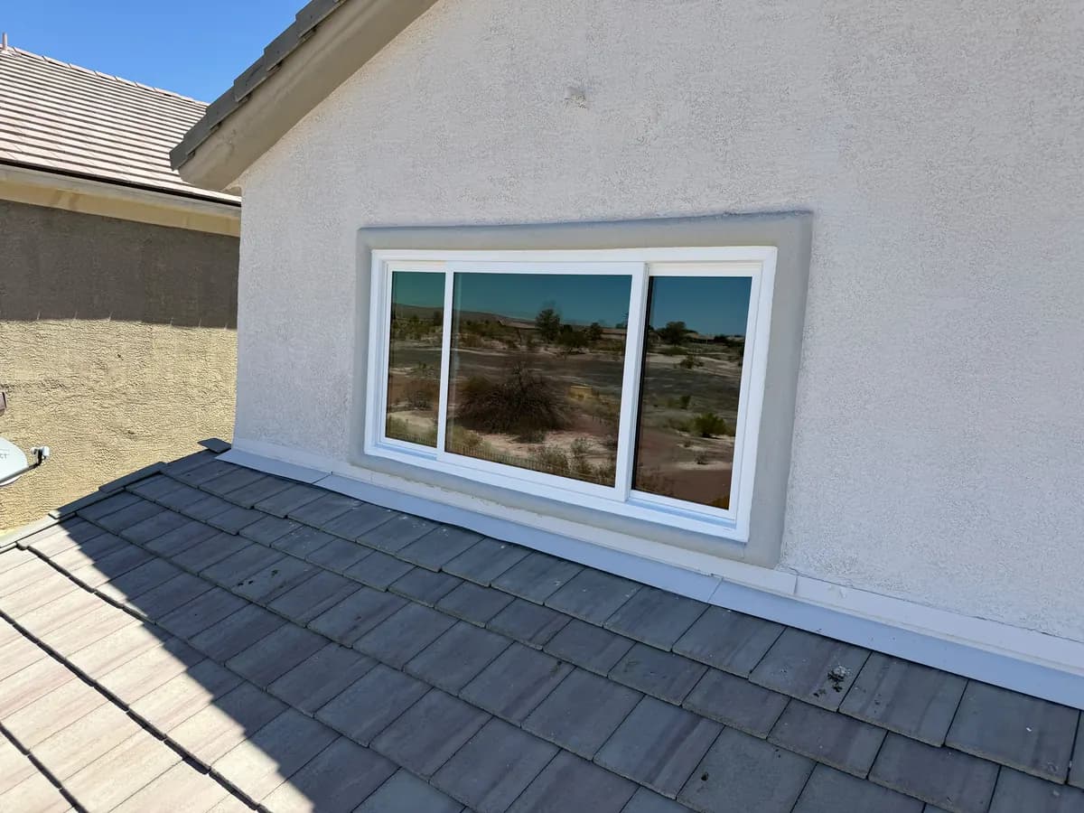 Wide white sliding window in a stucco wall.
